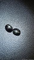 Two oval black star diopside cabochons on textured surface
