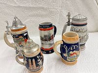 Five assorted ceramic beer steins displayed together