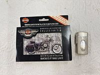 Harley-Davidson collector tin of playing cards alongside silver-tone lighter