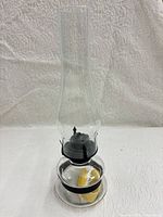 Full view of glass hurricane oil lamp with chimney attached