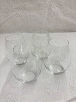 Four clear Riedel stemless wine glasses on white backdrop