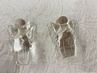 Two clear glass angel figurines on cloth surface