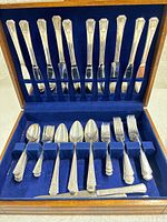 open flatware chest showing knives in lid and assorted utensils in base