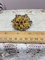 Front view showing gold-tone flower design, stones, pearls and ruler for scale