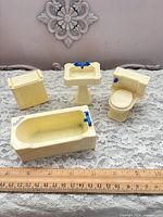 Full view of four cream plastic bathroom pieces with ruler for scale
