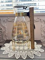 Full view of carafe on stand beside ruler showing height