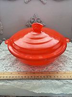 Front view of red covered casserole dish with ruler showing diameter