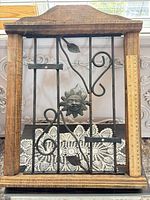 Front view of rectangular wood-framed wrought iron wall candle holder with sun face