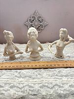 All three off-white bisque half dolls lined up with ruler for scale