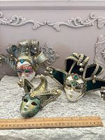 All three Venetian jester masks on lace cloth with ruler for scale