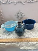 Three items: glass casserole with lid, enamel pot, stoneware vase, ruler for scale