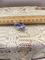 Front view of silver-tone cat brooch beside ruler showing 1.5 inch length