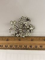 Front view of rhinestone brooch next to ruler showing size