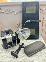 Full group shot of camera, flash, ledger, eyeglass case and totem