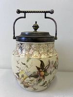 Front view of porcelain biscuit jar showing floral decoration, crackle band, metal lid and handle