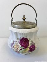 Front view of porcelain biscuit barrel showing floral design and metal lid with handle