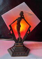 Lamp illuminated showing amber glow through diamond shade, nude figure front view