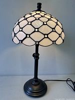 Full view of lamp on table, showing base, column, and stained glass shade