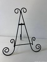 Front view of black cast iron easel with scroll feet and top