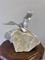 Front angle of silvered metal bird on stone base