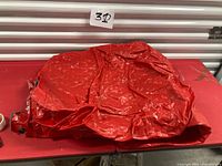 Deflated red air mattress showing full surface, valve visible