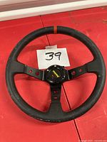 Front view of black leather Momo steering wheel showing horn button and orange centering stripe