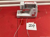 Front view of Singer Lockstitch 2000 compact sewing machine on red surface with power cord visible