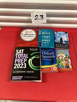 Top-down view of six books arranged on red surface with lot number card