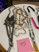 Group shot of necklaces on white surface with note 45