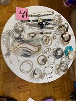 Overview of full lot on white table showing variety of jewellery and watches