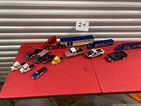 Group shot of all toy trucks, trailers and cars on red tables