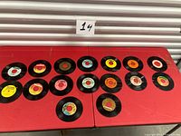 All sixteen 45 RPM vinyl records laid out on table