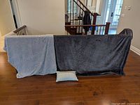 Both blankets draped on railing with accent pillow below