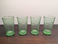 Four green pint glasses front embossed crest visible
