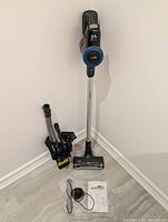 Vacuum assembled upright with accessory cluster, charger and manual on floor