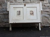 Front view showing cabinet shape, panelled door, ring pull, distressed paint