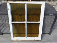 Front view of stained glass window showing four yellow panes and white wooden frame
