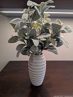 Vase standing upright with faux greenery inserted