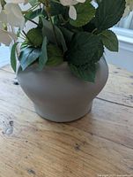 Side view of grey ceramic vase with faux hydrangeas
