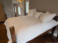 Full view of king bed showing white quilted bedspread and pillows