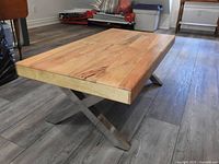 Angled side view showing wood top thickness and stainless steel X legs