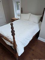 Full view of queen bed with white leaf-pattern quilt and pillows