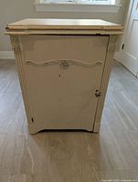 Front view of white antique cabinet showing decorative door and moulding