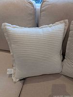 Front view of first white ribbed pillow on couch