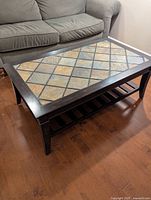 Angled view of coffee table showing tile top, wood frame, and under-shelf