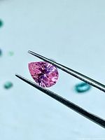 Close-up of pear-shaped pink cubic zirconia held by tweezers