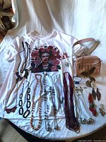 Group shot showing T-shirt used as backdrop with jewelry, belt bag and ashtray