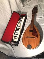 Melodica in open case beside mandolin on bed