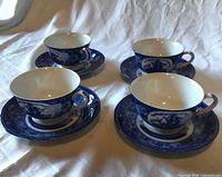 Four blue and white transferware teacups on matching saucers