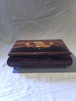 Closed wooden inlaid jewelry box showing marquetry lid and keyhole front
